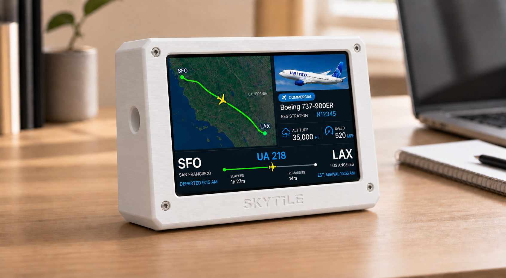 SkyTile showing a live flight on a warm wooden desk beside a laptop